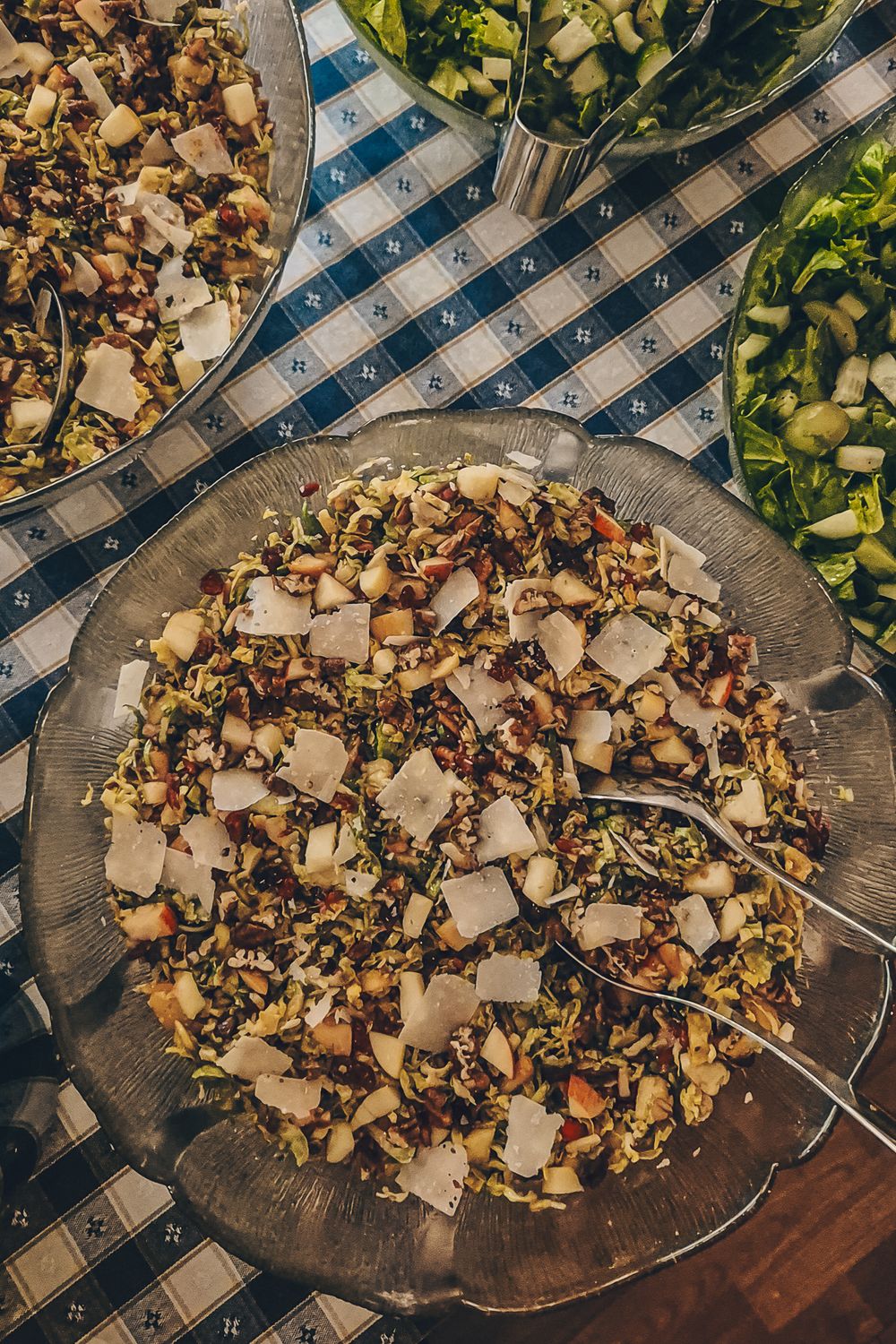 Mixed salad with chopped vegetables and nuts served on a glass plate with checkered tablecloth.