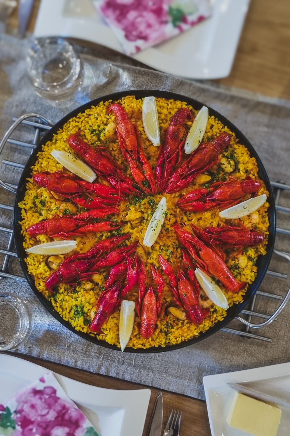 A vibrant paella dish with red crawfish arranged in a star pattern on yellow saffron rice.