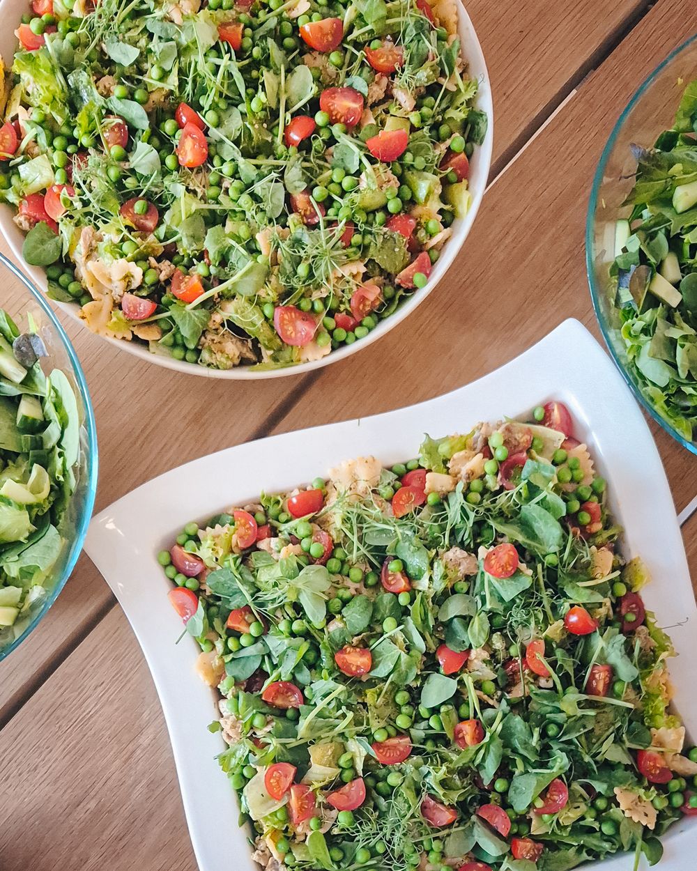 Colorful quinoa salad bowls with fresh arugula and cherry tomatoes served on a wooden table.
