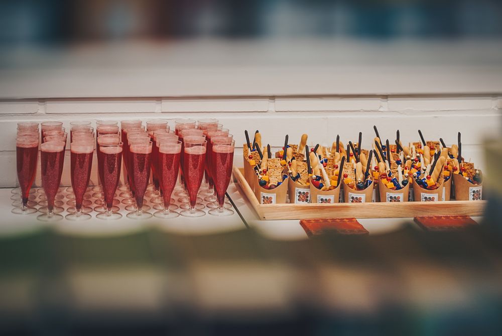 Row of pink cocktails and appetizer bites arranged on serving trays.