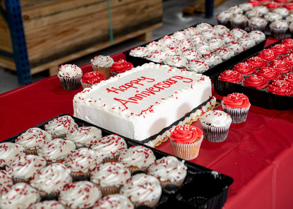Display of decorated cupcakes and celebration cake on red tablecloth.