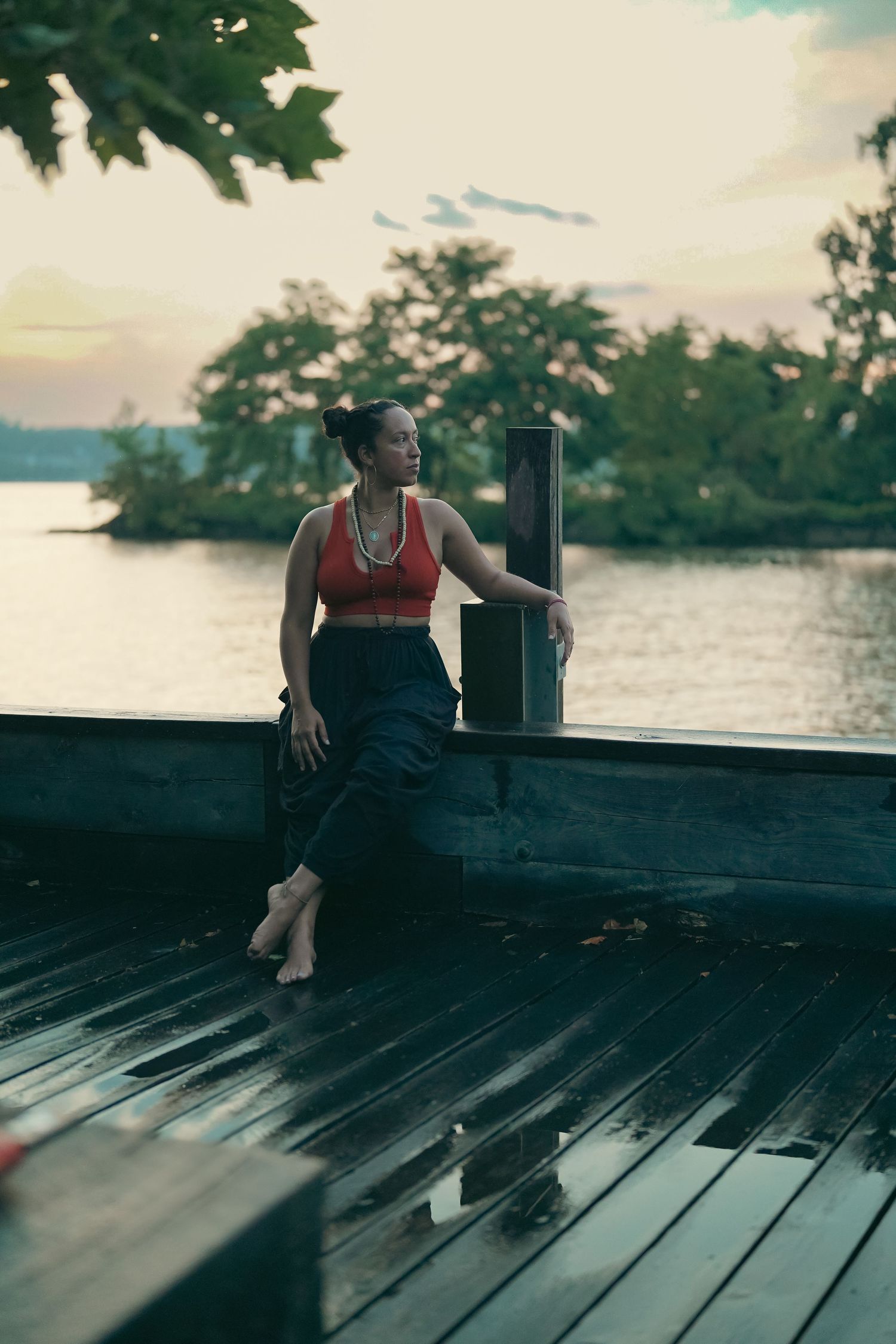 Person relaxing on wooden dock by lake at sunset.