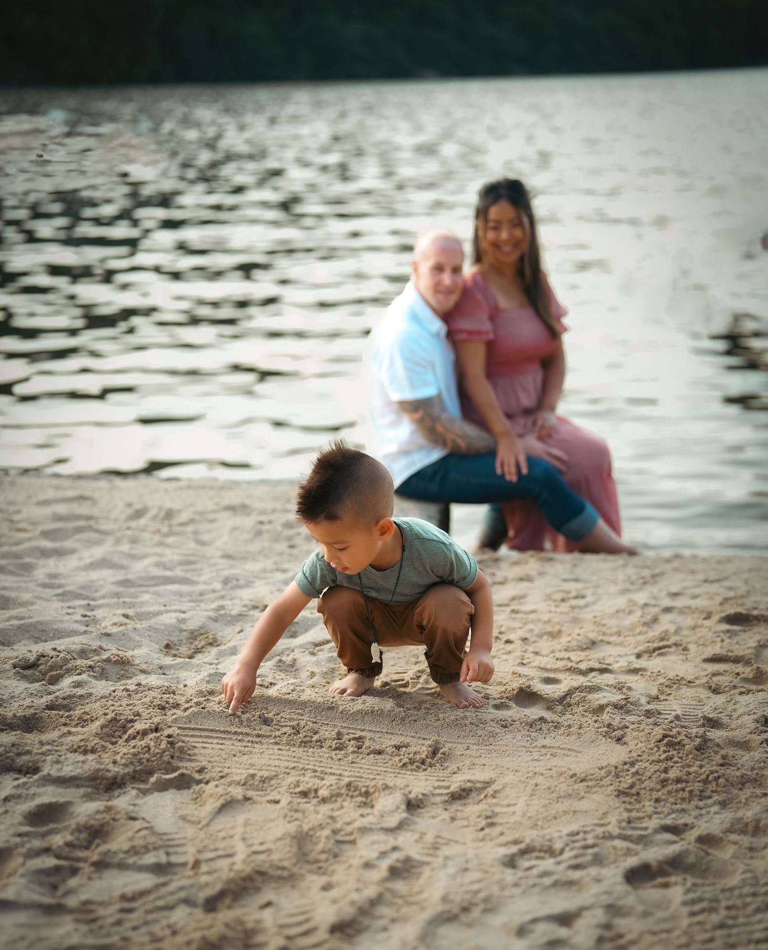 Child playing in the sand at the beach during sunset.