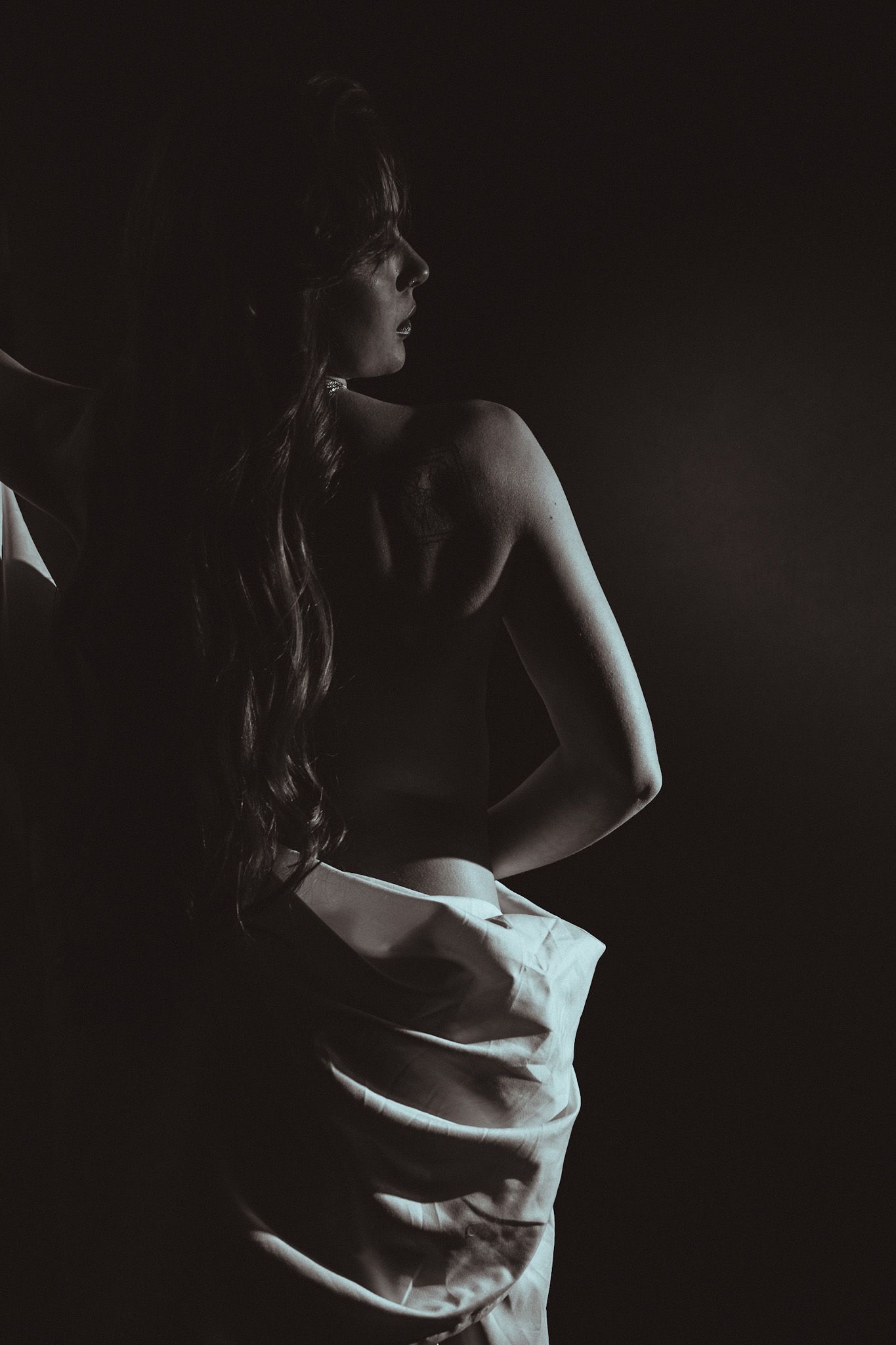 Dramatic low-key portrait in white fabric against dark background.