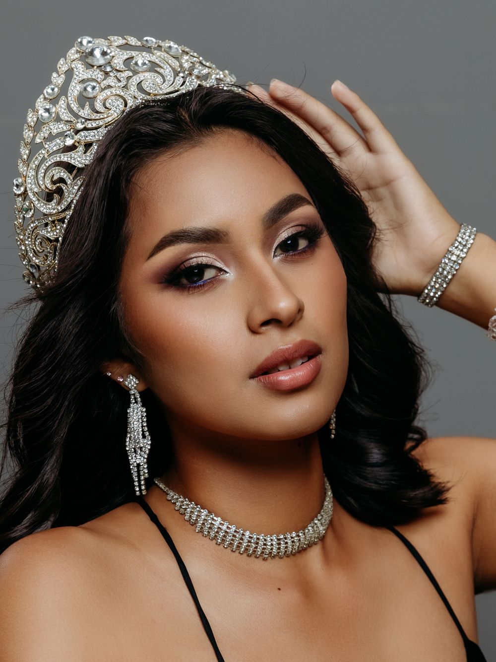 Close-up beauty portrait of a model wearing ornate crystal crown and jewelry.