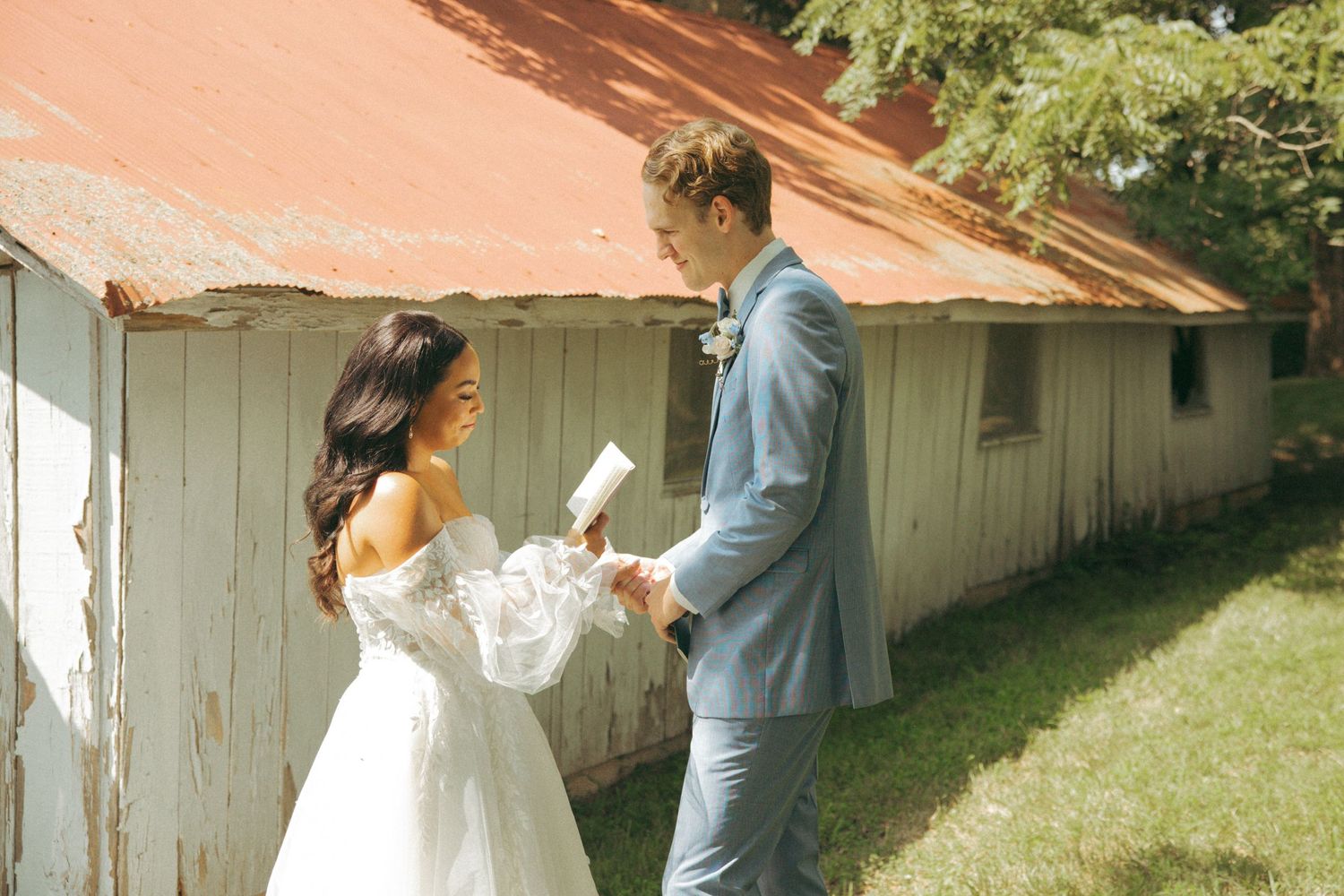 Couple reading personal messages to each other during outdoor wedding ceremony.