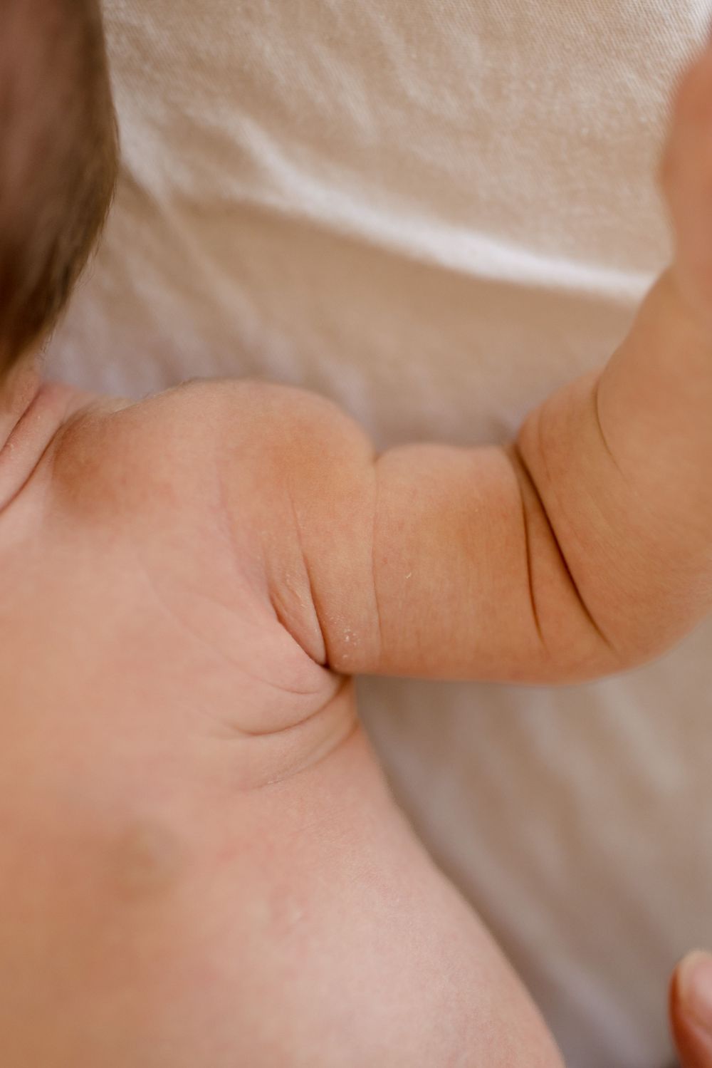 Gros plan de la peau douce du bébé et des petits bourrelets sur le bras sur fond blanc.