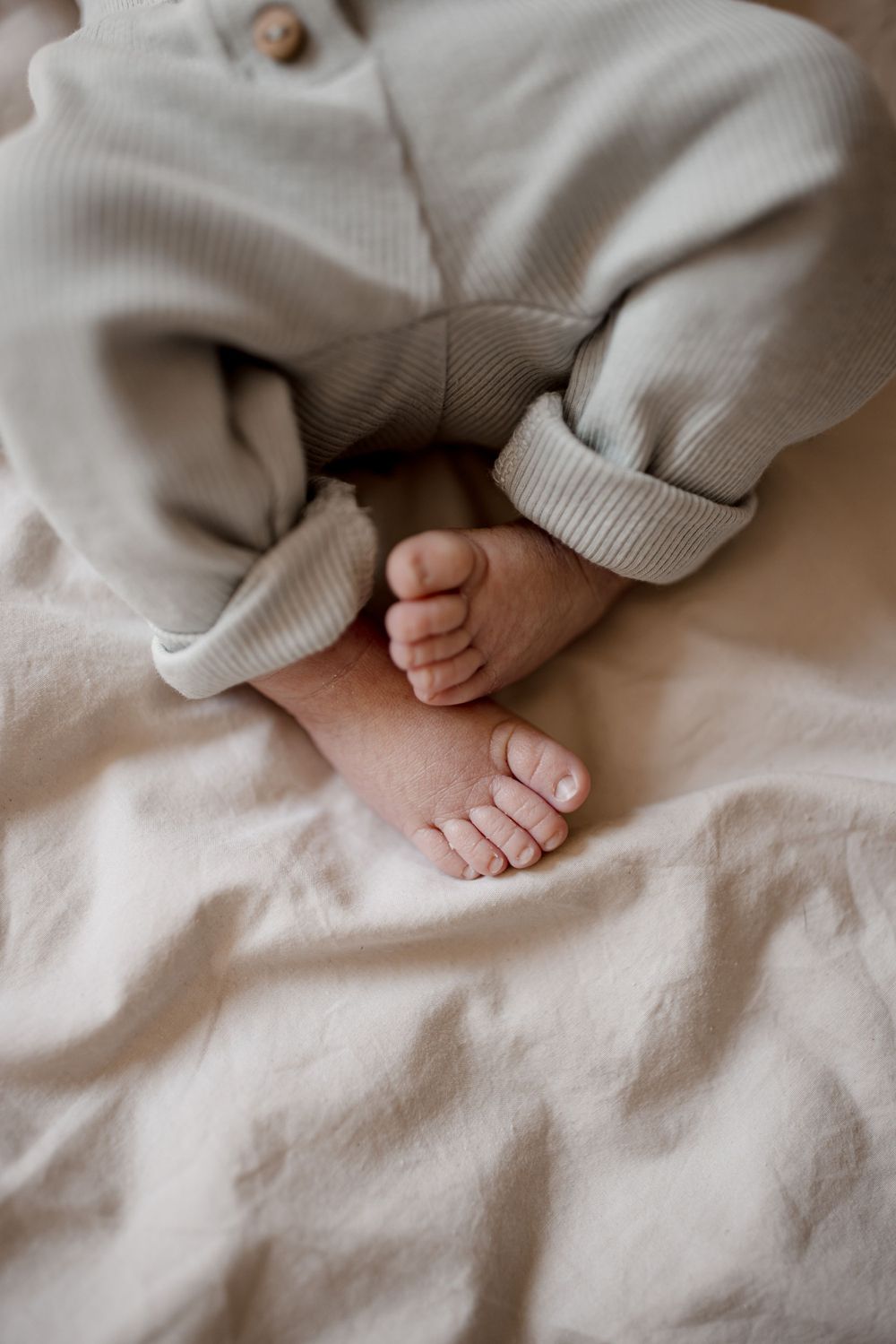De minuscules pieds de bébé reposent sur une literie blanche.
