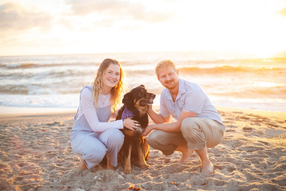 Family with dog enjoying sunset on beach together.