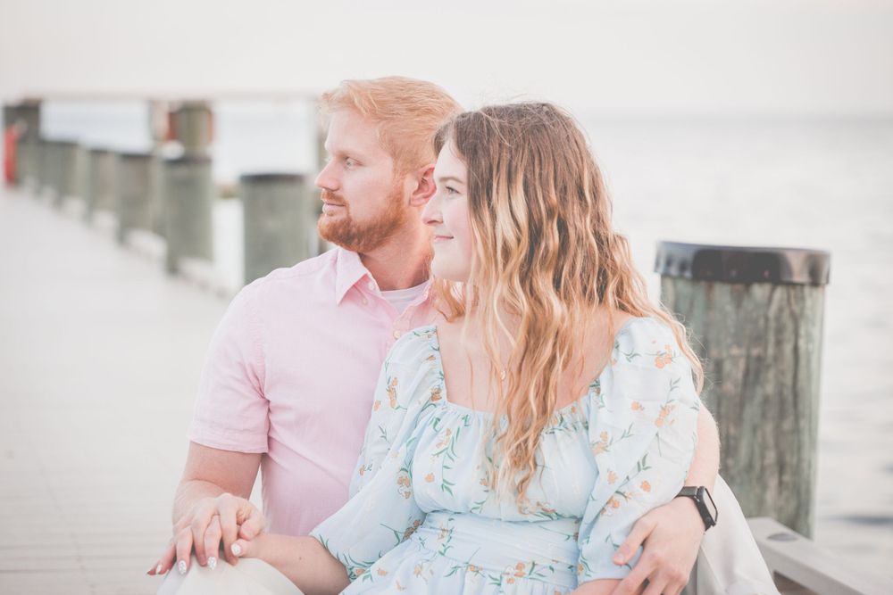 Romantic couple sitting together on wooden dock during sunset.