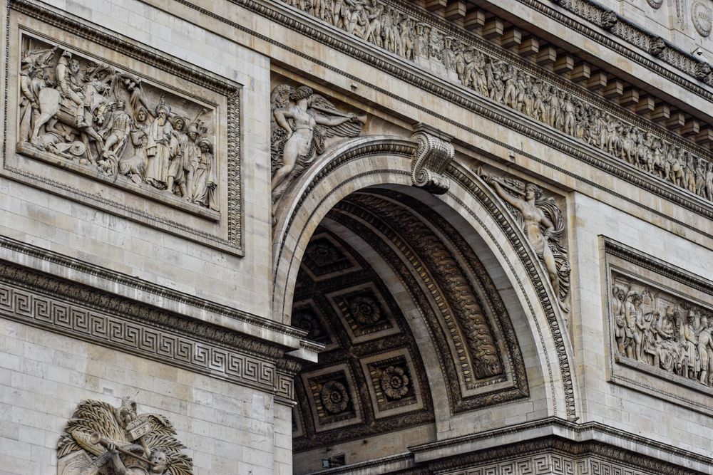 Detailed architectural relief and carved stonework on the Arc de Triomphe in Paris showing classical design elements.