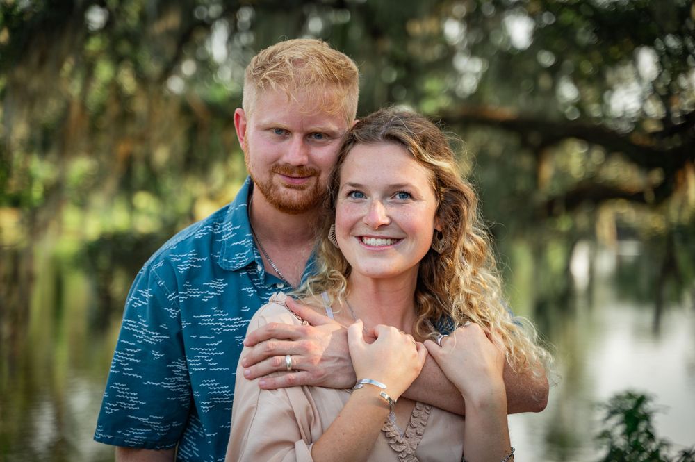 Couple sharing intimate moment in front of lush green background.