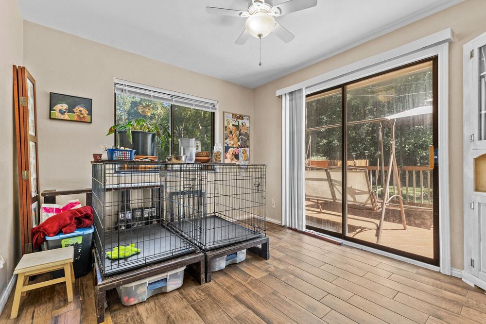 Bright bonus room with hardwood floors, ceiling fan, sliding glass door leading to backyard deck area.