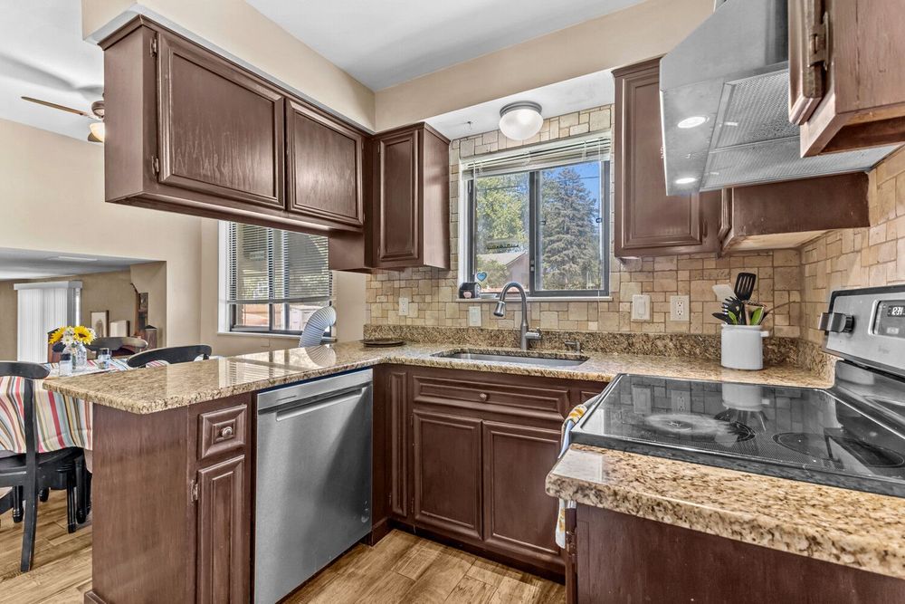 Kitchen with dark wood cabinets, granite countertops, stainless steel appliances, and tile backsplash.