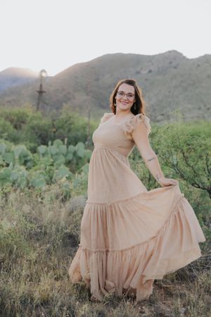 Twirling beige dress captured in a desert setting with mountains and cacti creating a dreamy backdrop.
