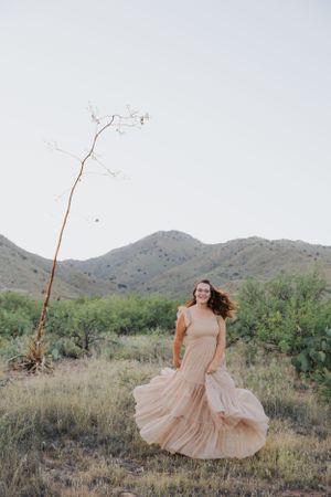 Desert fashion photography with flowing dress movement against mountain backdrop and native flora.
