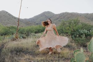 A flowing dress catches the wind in a dramatic spin among desert flora and mountains.