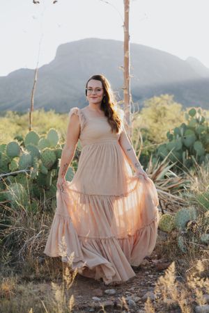 Ethereal desert photography with flowing dress against mountain backdrop.