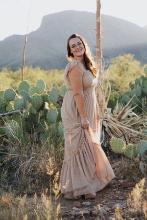 Desert fashion photography featuring tiered maxi dress among cacti and mountains.