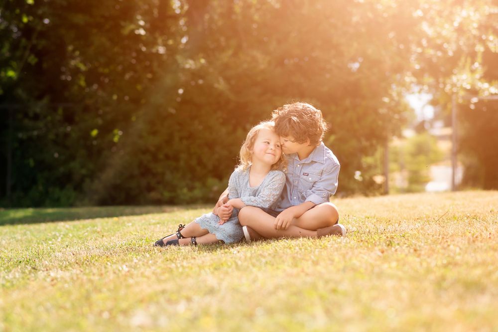 Two people sit together on grass during golden hour sunset.