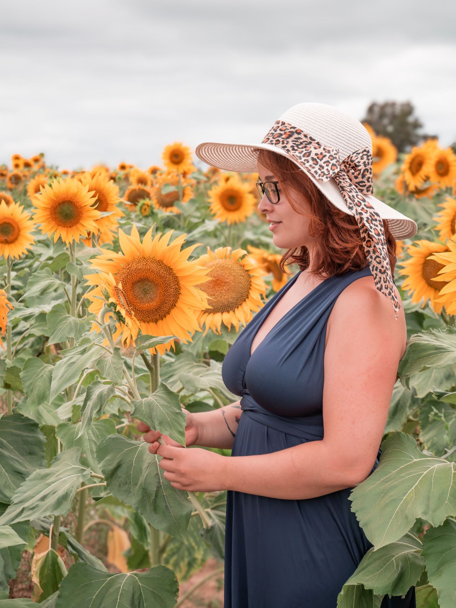 Une jeune femme dans un champs de tournesols avec un beau chapeau