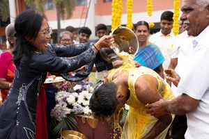 A woman pours turmeric water over her son-in-law's head at the end of his Haldi celebration.