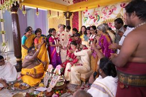 Standing loved ones throw flower petals over a seated newlywed couple at a South Indian (Tamil) wedding.