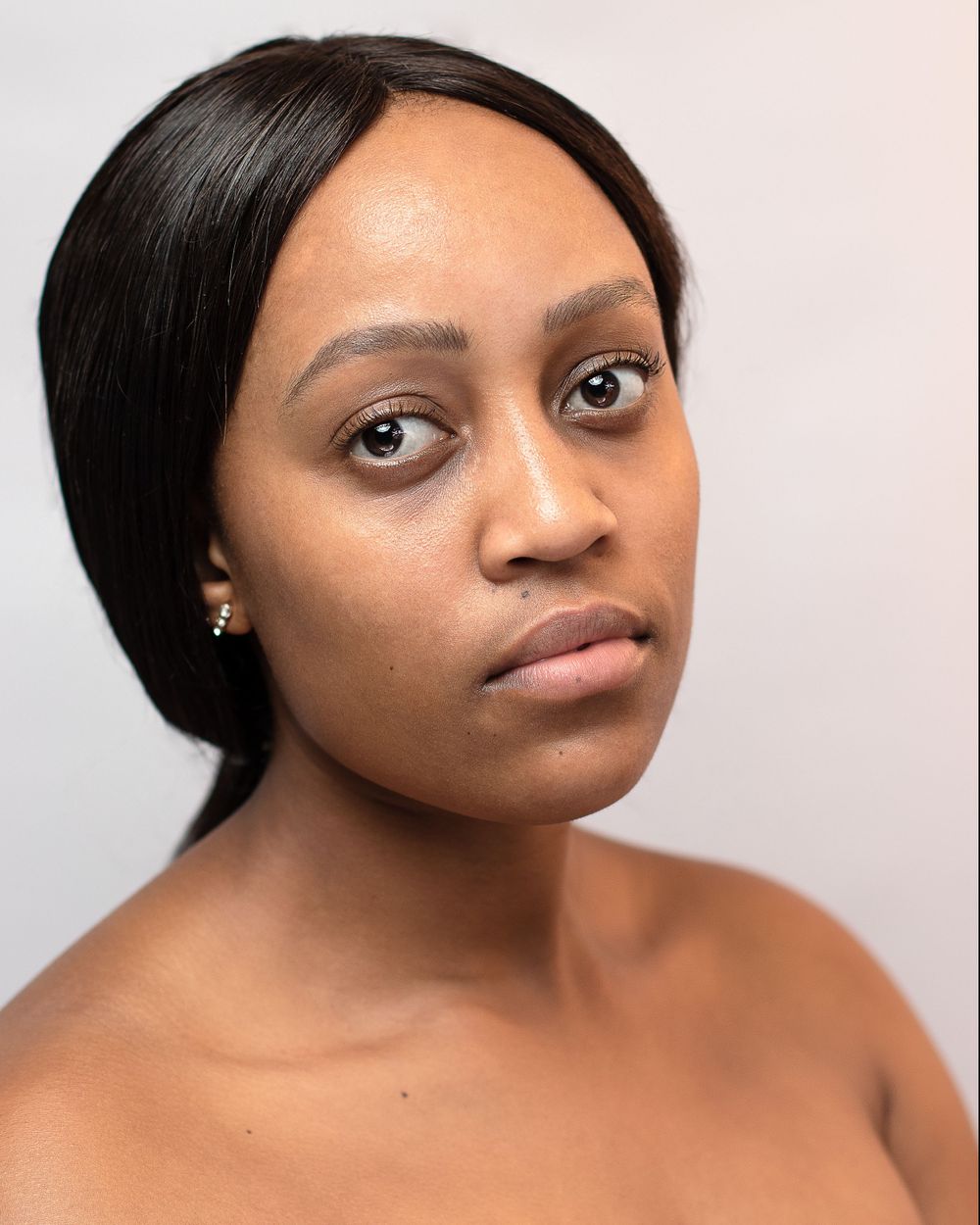 Professional headshot of a woman with bare shoulders against neutral background.