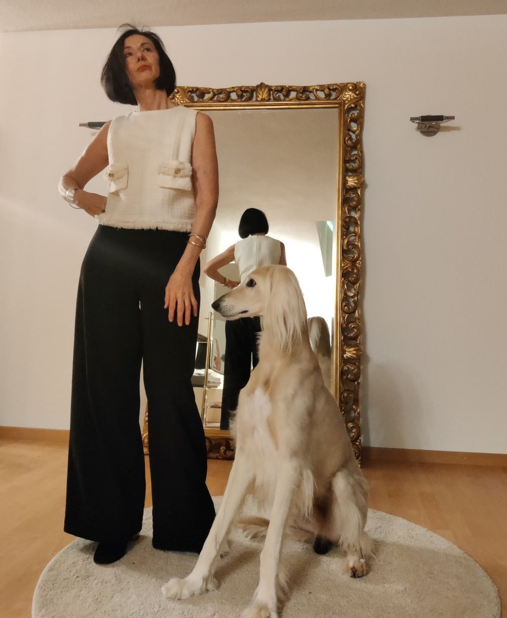 Sonnia Geiger zusammen mit einem Windhund. Sie trägt eine schwarze Hose und helles Oberteil.