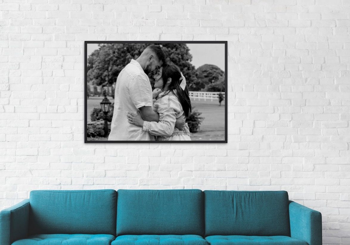 Contemporary living room featuring a teal blue sofa against white brick wall with framed photos.