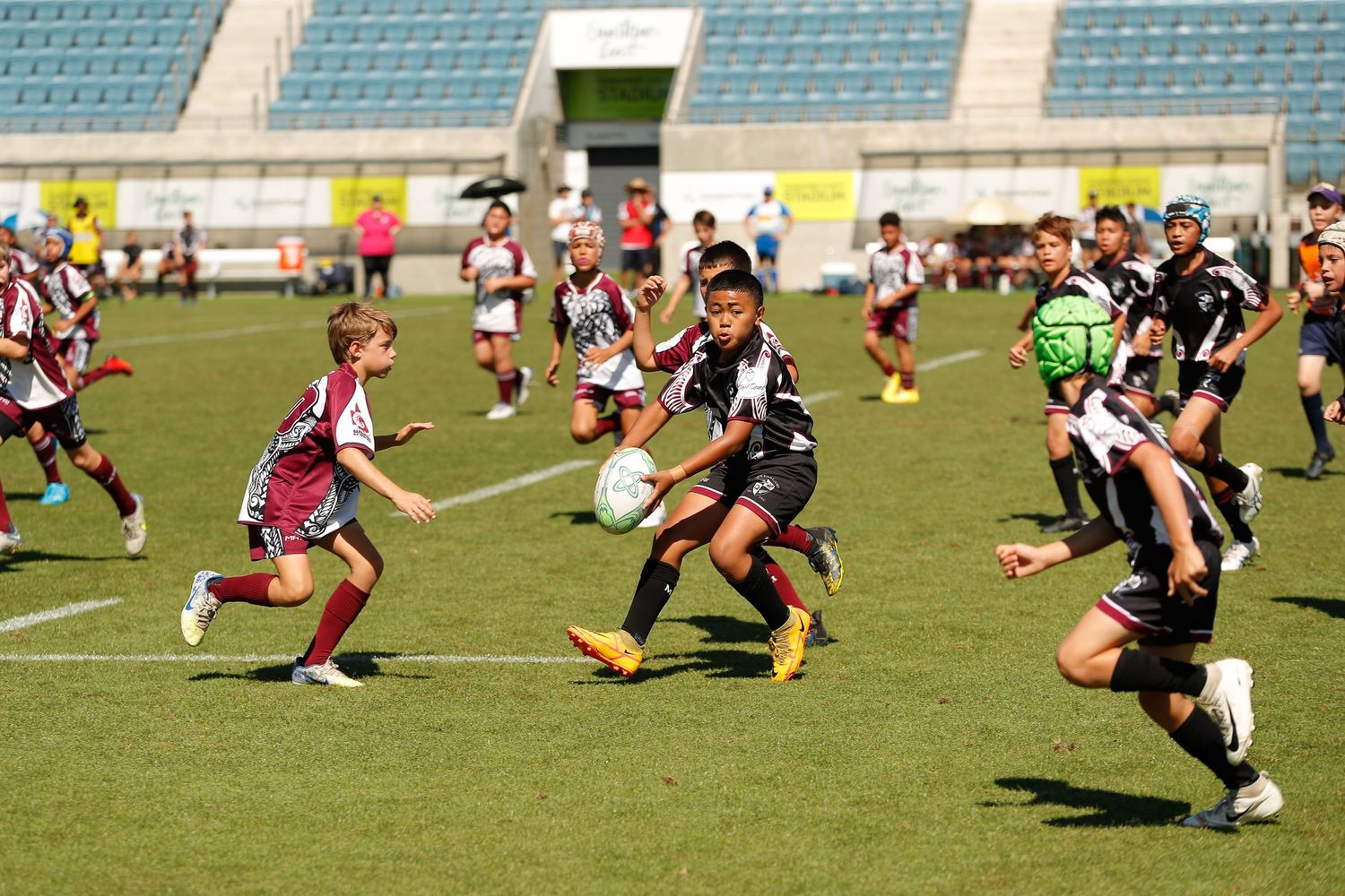 Rugby players compete for ball possession during match on grass field.