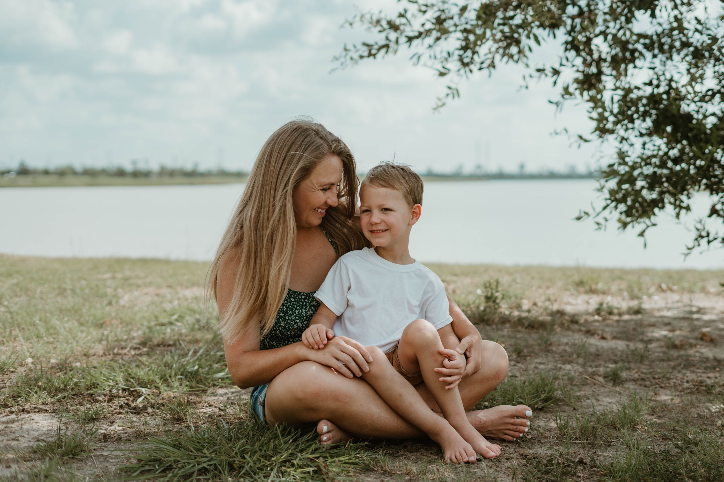 Serene lakeside portrait with green top and casual styling against water backdrop.
