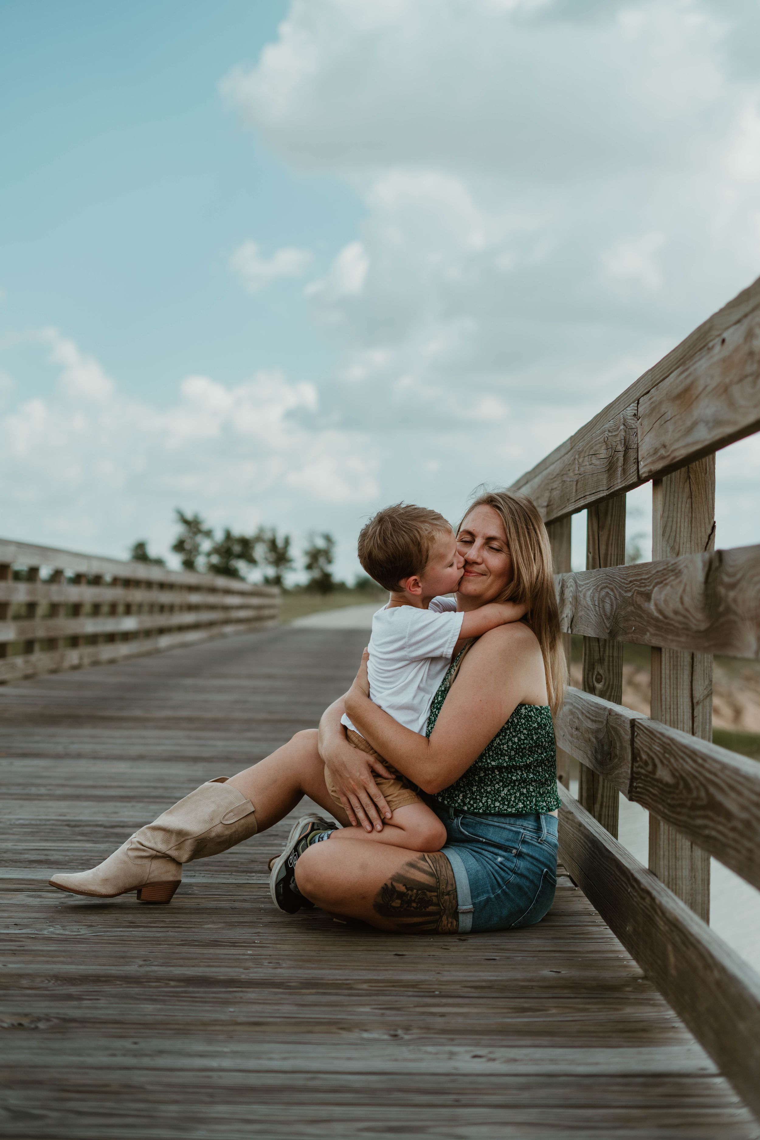 An intimate moment shared on a wooden boardwalk overlooking the water.
