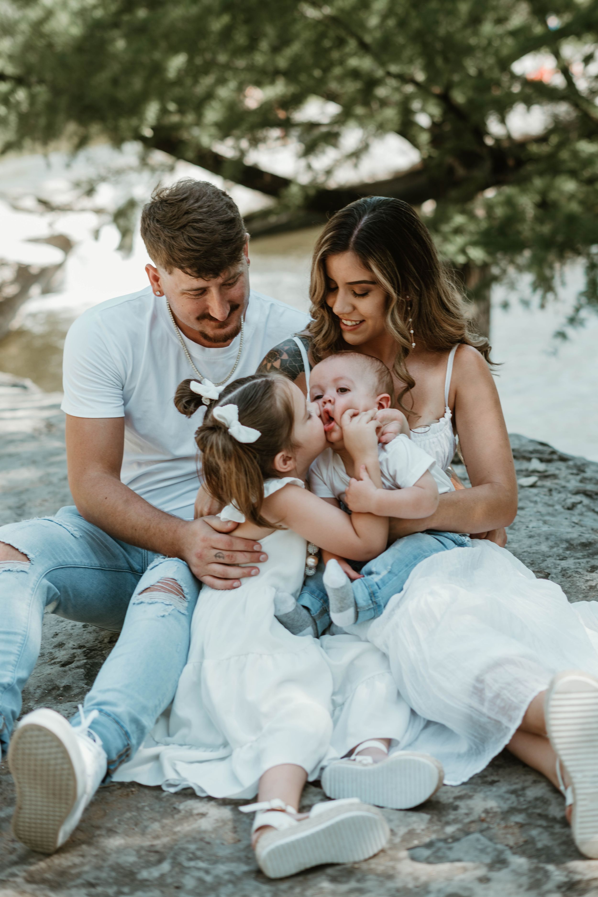 A family sharing tender moments together while sitting on coastal rocks.
