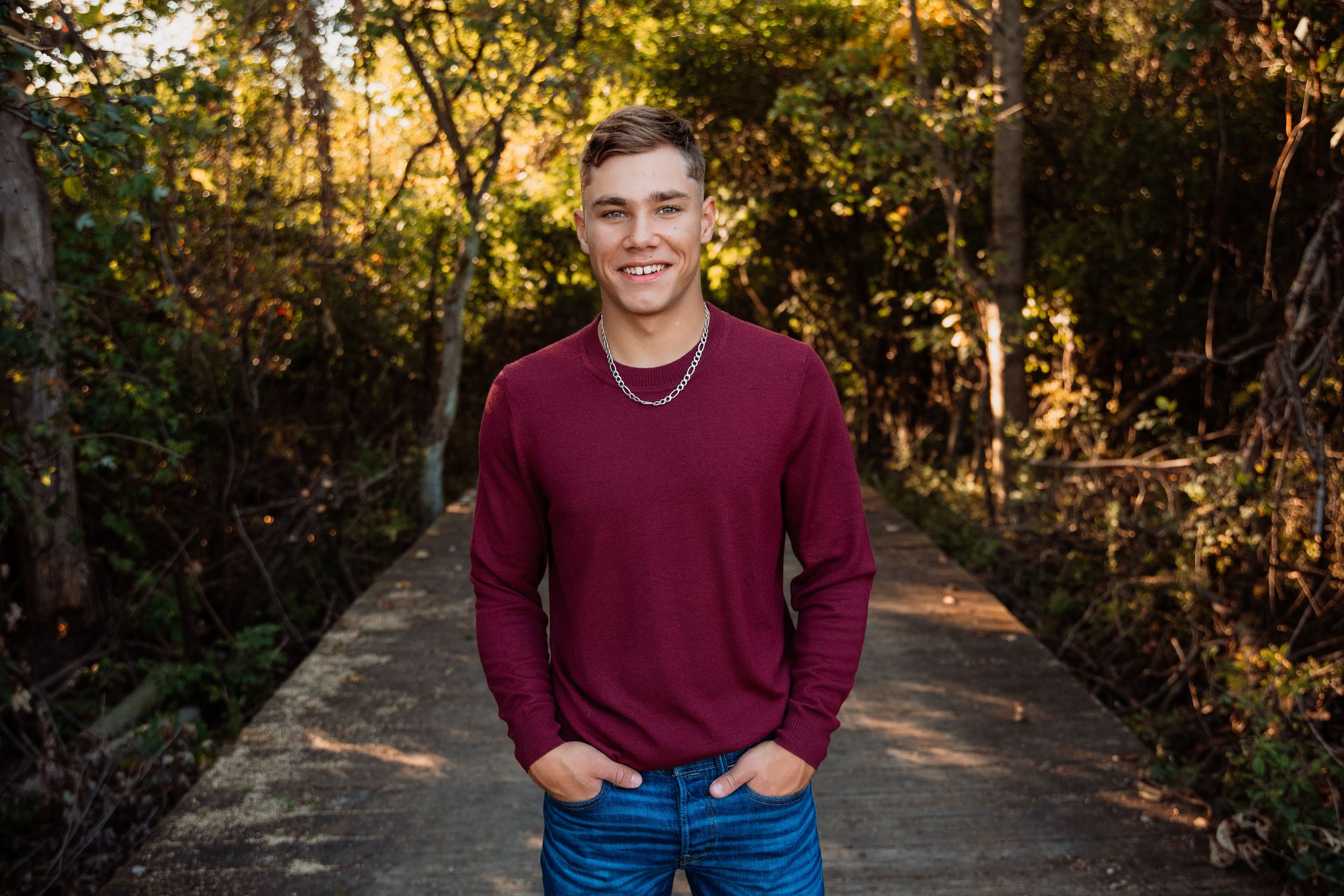 Outdoor autumn portrait session on a tree-lined path with warm golden lighting.