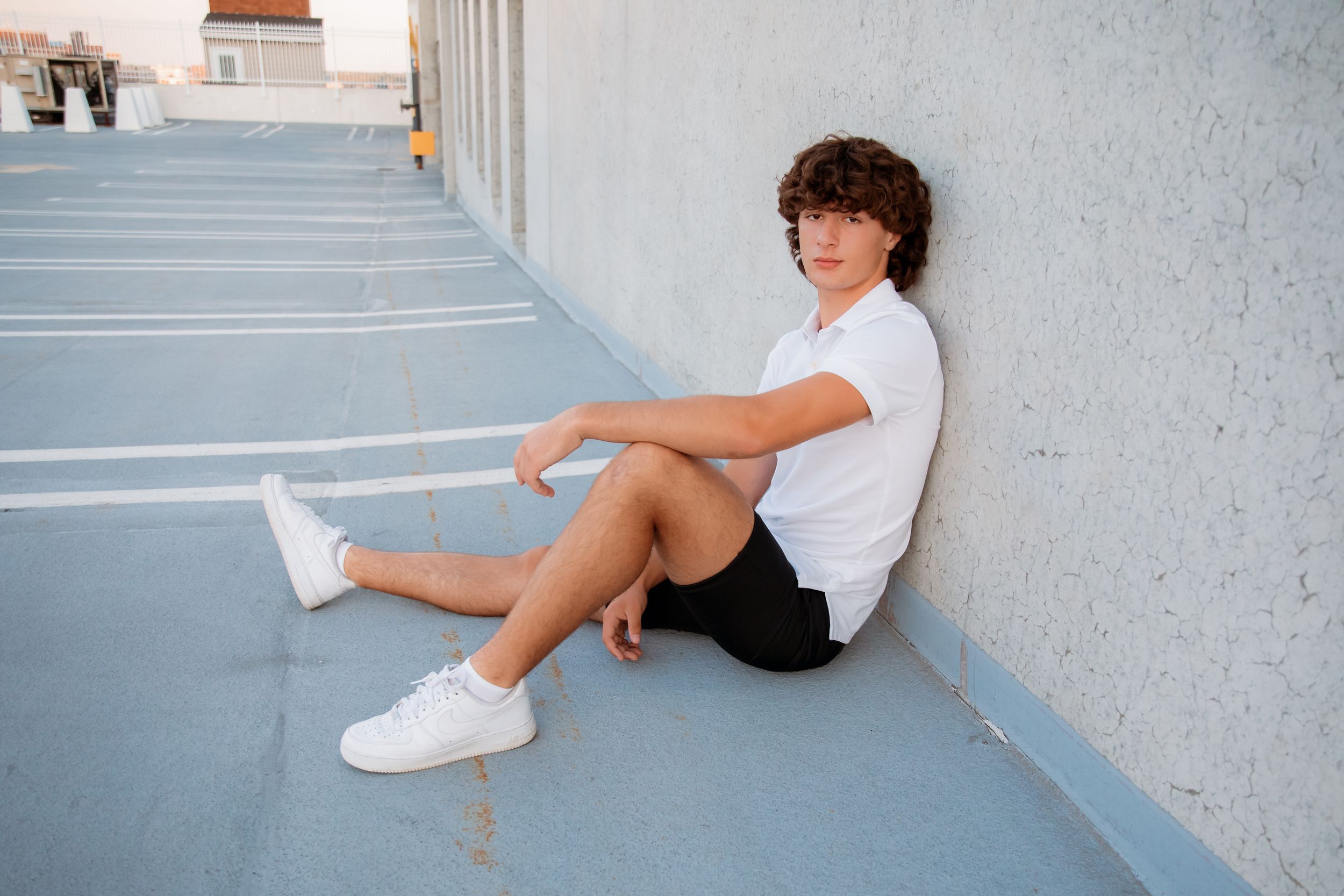 Casual portrait session against a light gray wall in an urban setting.