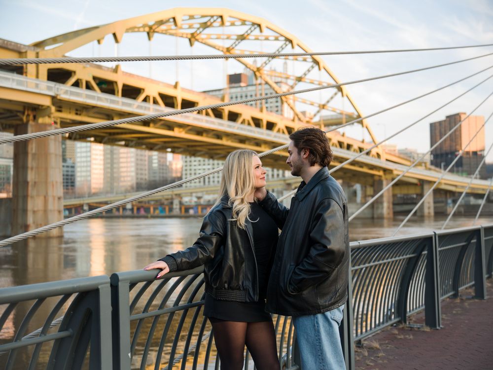 Person in a dark coat walks along a curved bridge railing during golden hour lighting.