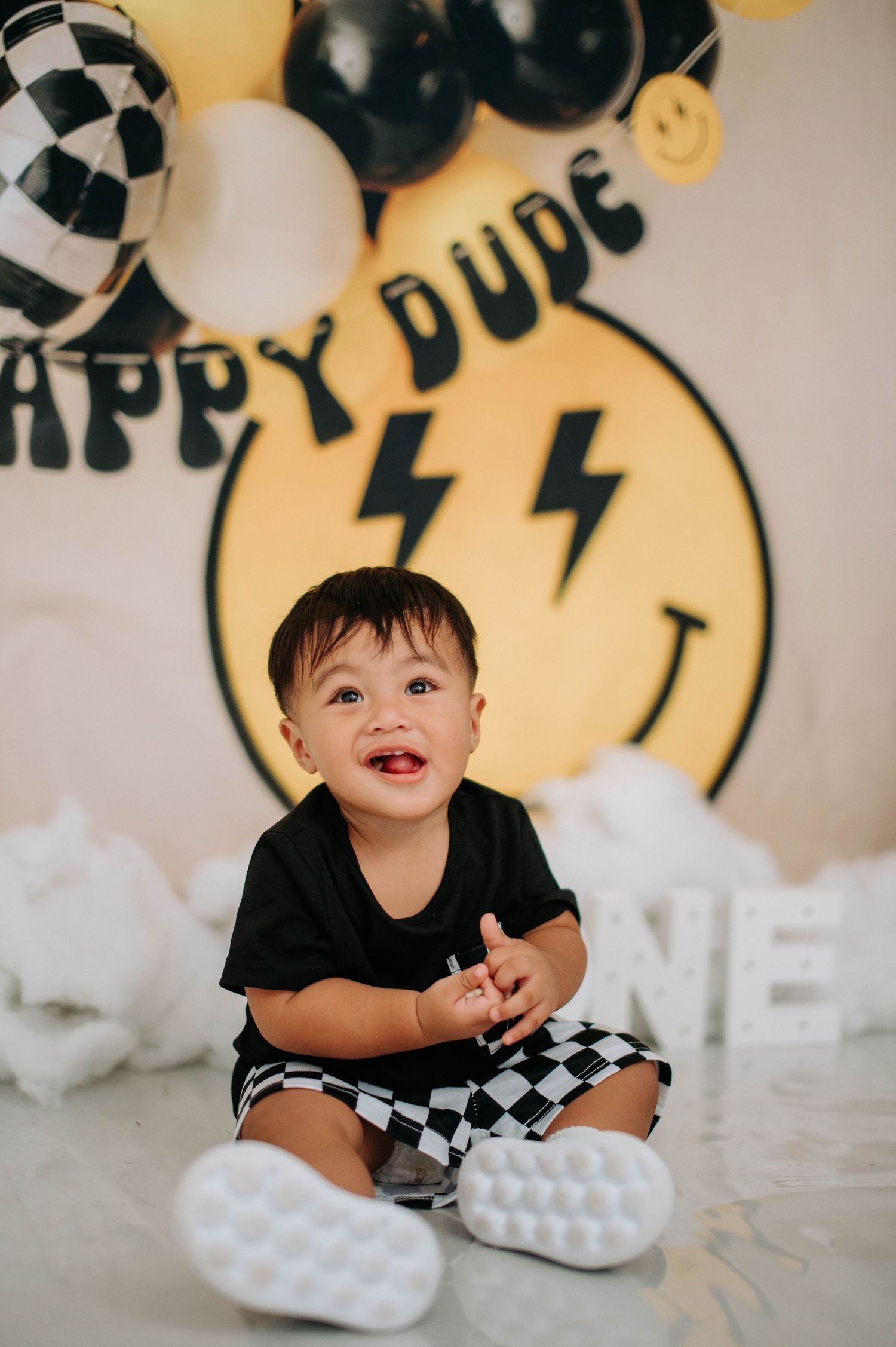 Happy party decorations with checkered balloons, lightning bolt emoji backdrop and fun black and white party details.