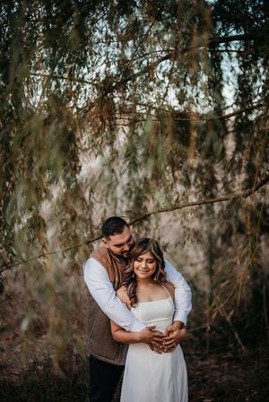 A romantic embrace photographed under the gentle cascade of willow branches.