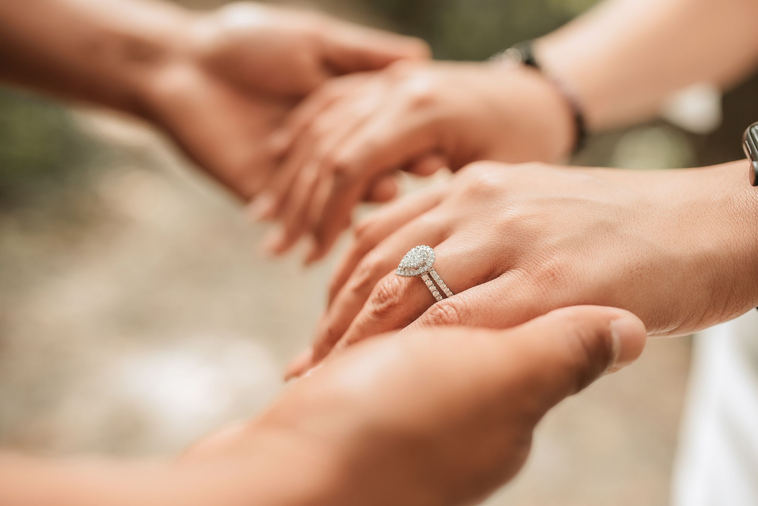 Close up of hands showing off engagement ring in natural lighting.