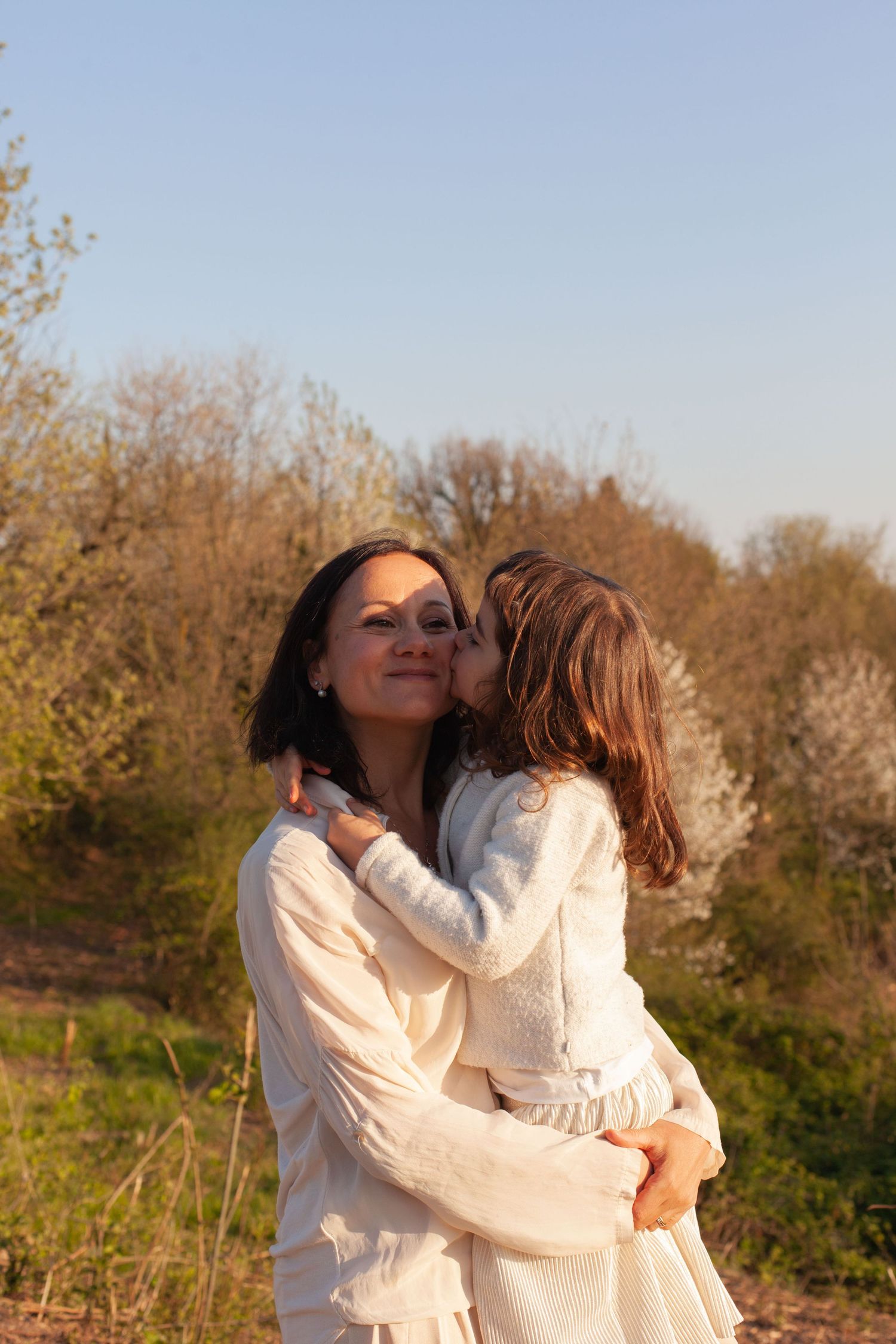 mamma sorride con sua figlia in braccio su un prato in Brianza. Sessione San Valentino in Brianza, sessione mamma e figlia in Brianza