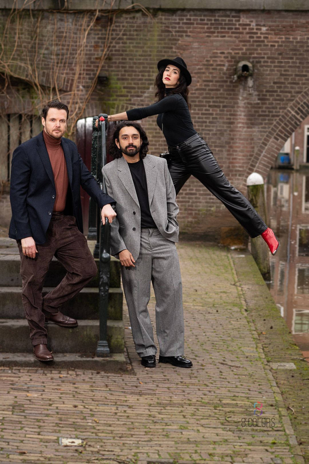 Three people posing on brick steps wearing stylish winter outfits including blazers and coats in an urban setting.