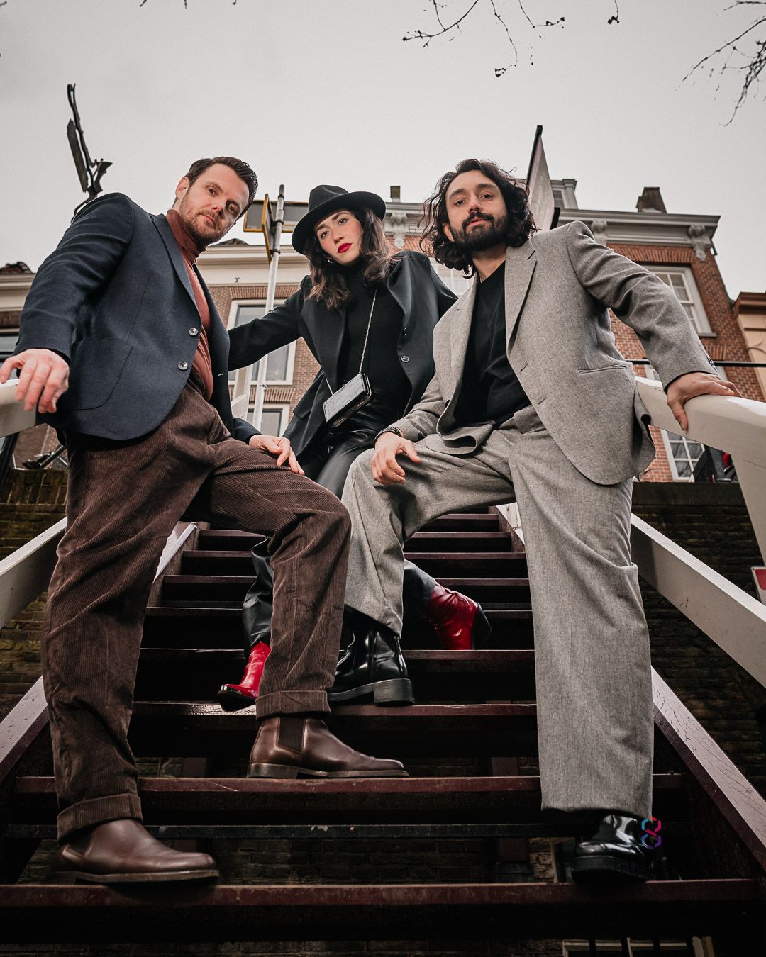 Three friends strike playful poses on outdoor wooden stairs in vintage-inspired outfits.