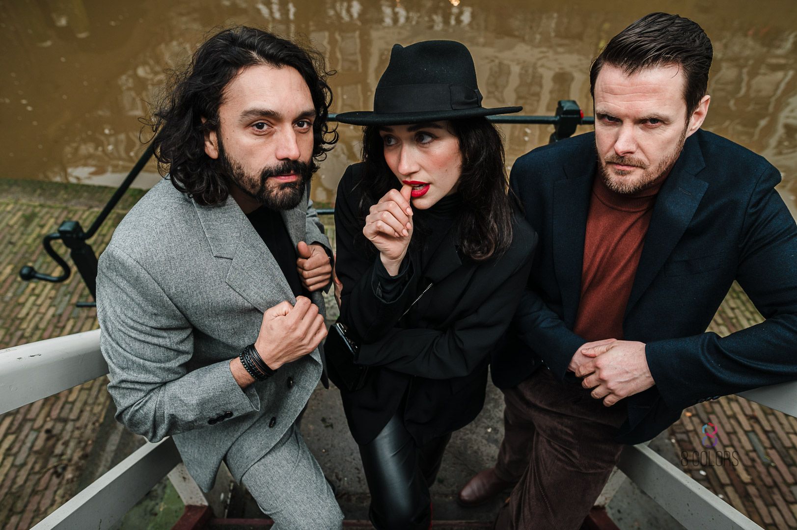 Group shot of three friends in stylish winter attire posing against a textured wall.