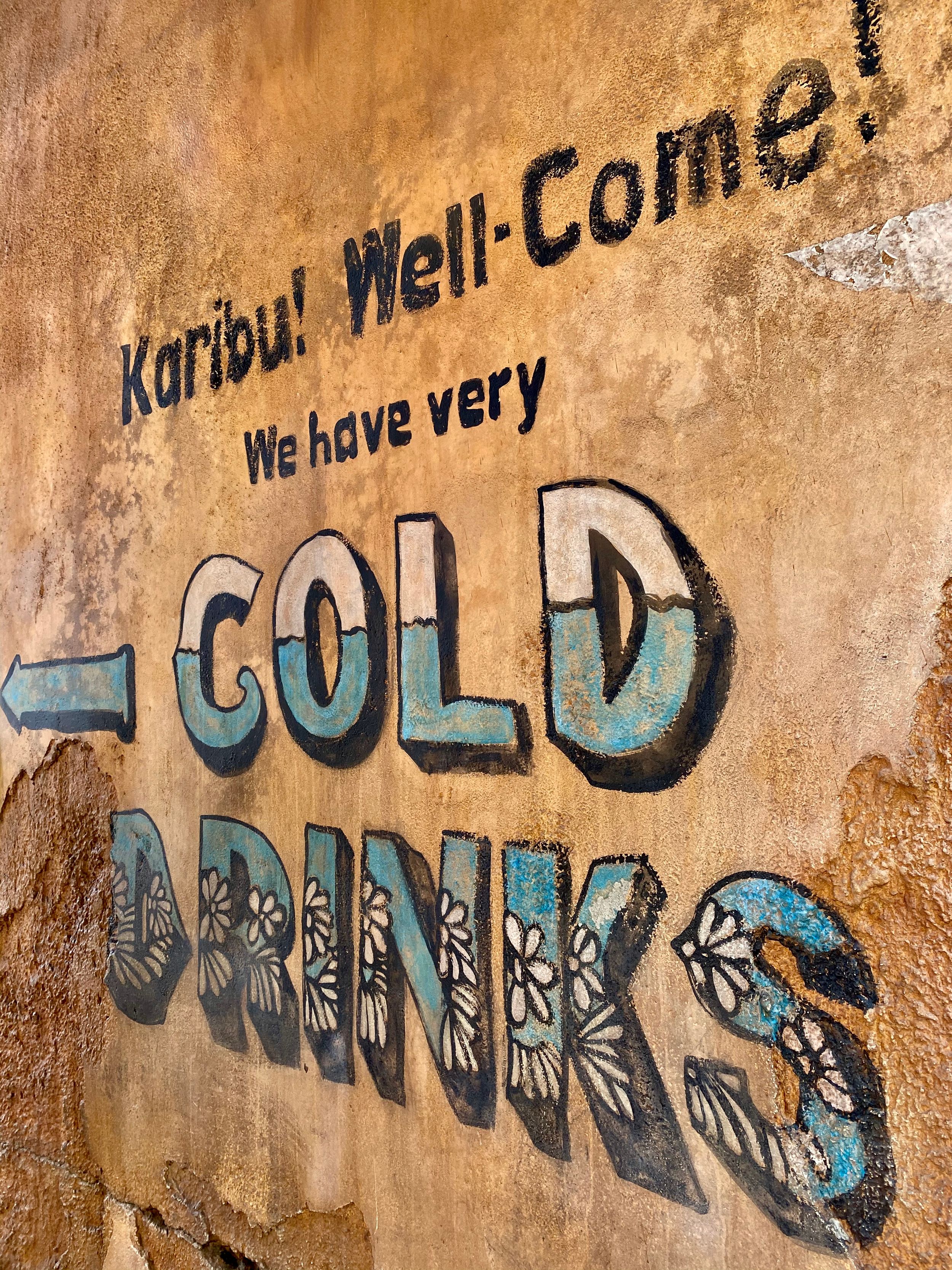 Weathered graffiti text in blue and white paint appears on a textured beige wall creating an urban art composition.