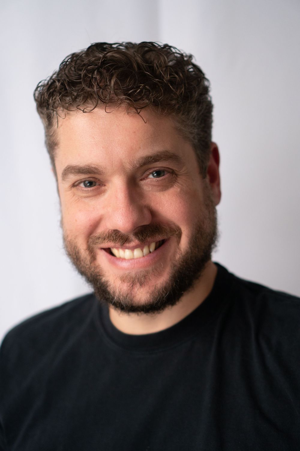 Casual close-up portrait showing warm smile against light background.