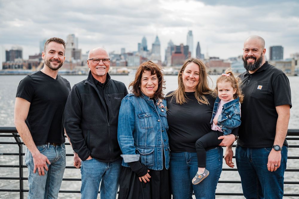 A group stands together on a rooftop terrace with the Philadelphia city skyline visible in the background.