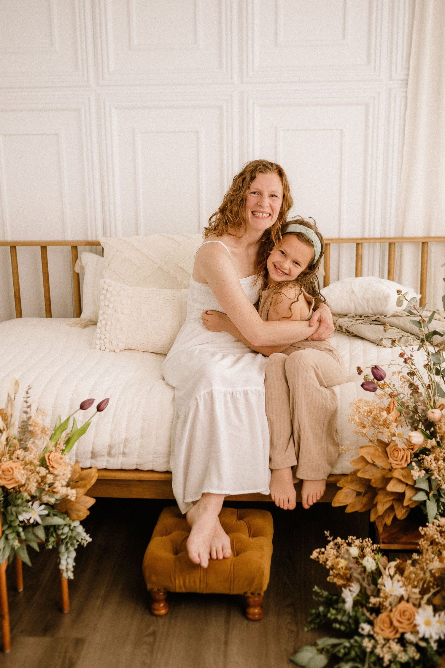 A cozy daybed scene with warm lighting features dried flowers and natural decor against white paneled walls.