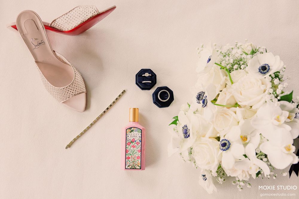 Flat lay composition of pink nail polish, delicate white flowers, blueberries and nude accessories on a pale background.