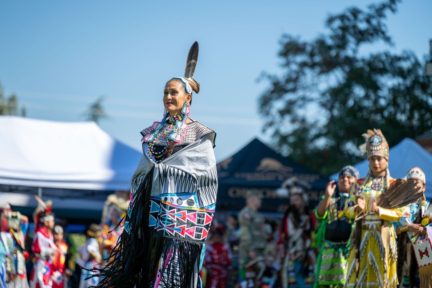 Traditional dancers perform in colorful regalia at an outdoor cultural festival.